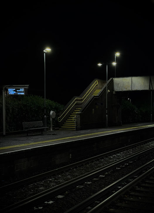 An empty train station at night, yellow safety lines are the only colours.