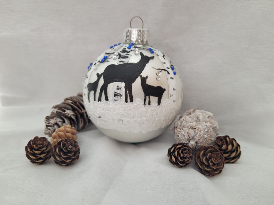 Painting of a deer family on an ornamental bauble.
