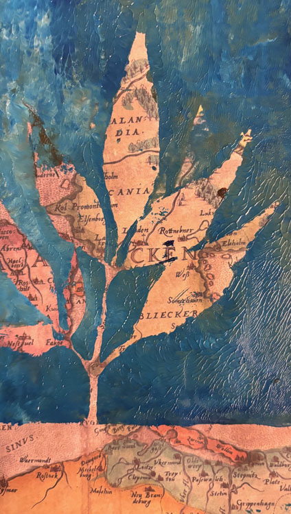 Painting on top of a map page showing a branch and leaves in the negative space.